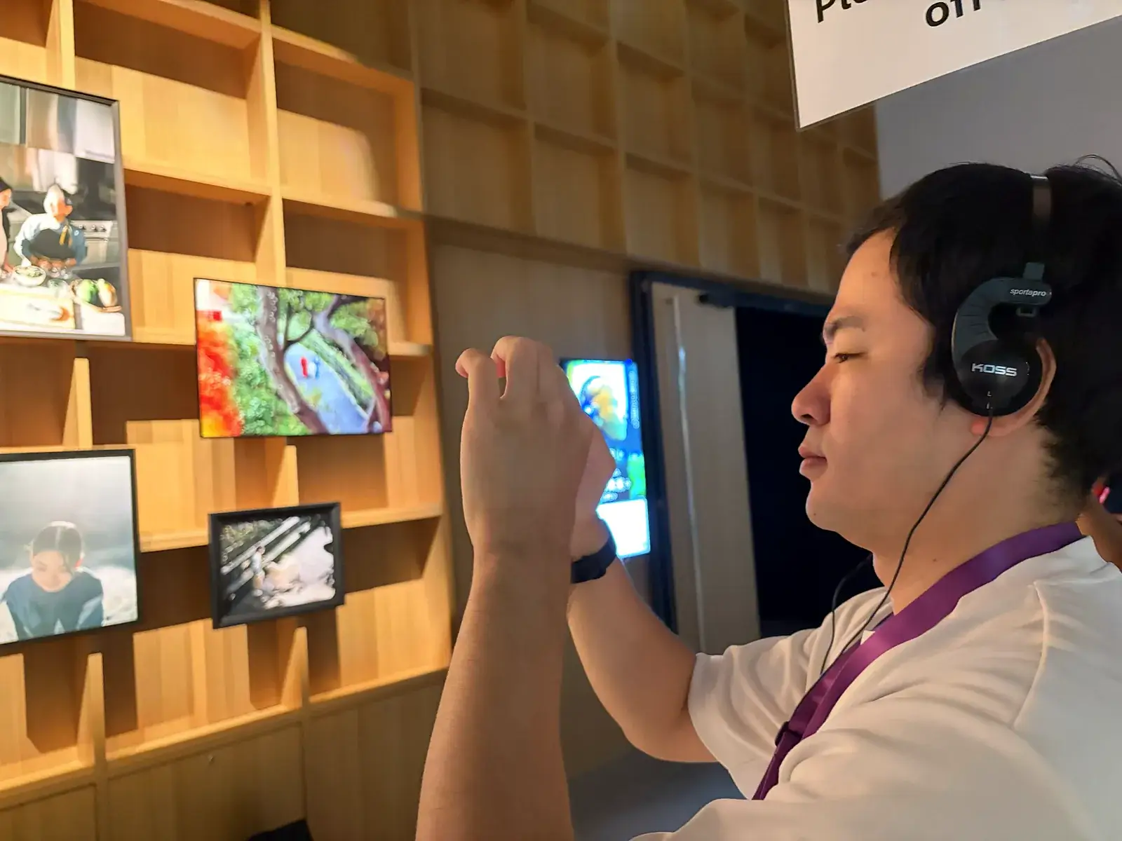 いのちの未来+で音声ガイドのヘッドホンをつけ、展示の写真の壁を撮影するおとぼけ