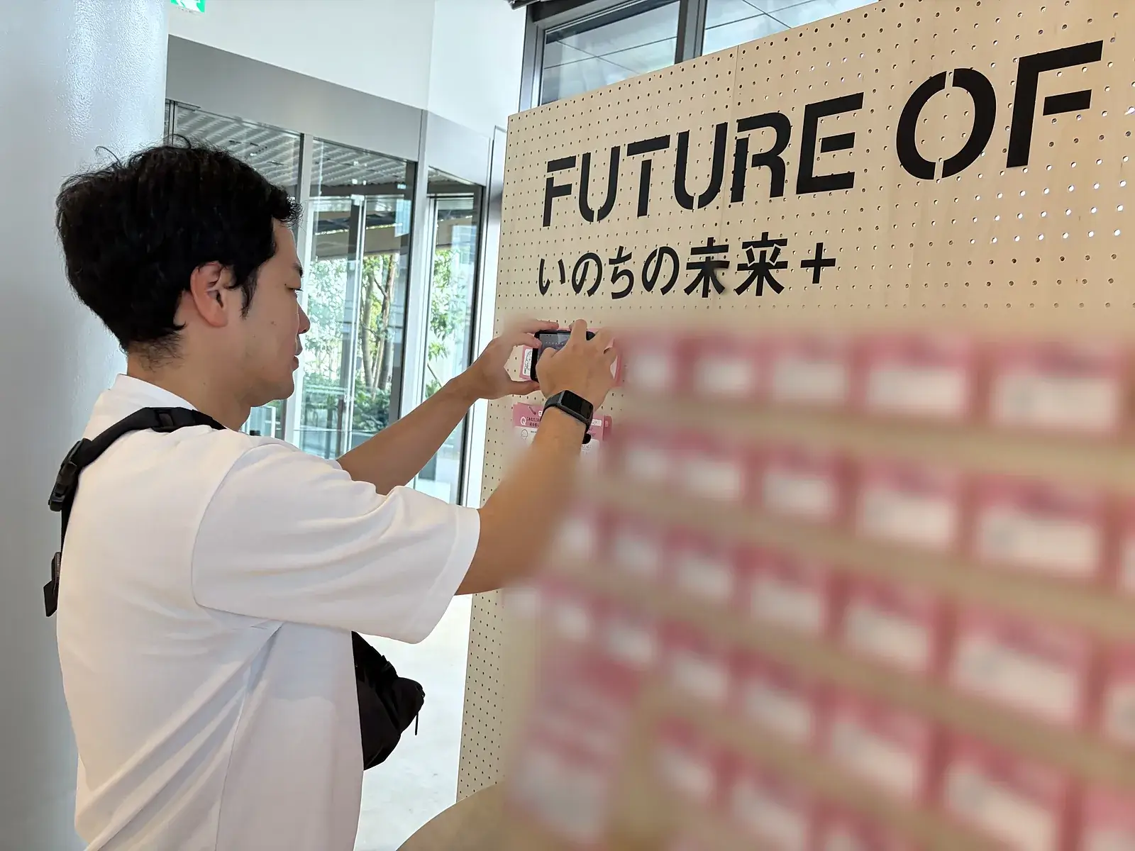 いのちの未来+の出口で、来場者が答えを書いたピンクのカードが並ぶ壁を撮影するおとぼけ